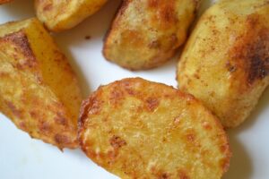 Patate al forno croccanti in una teglia, dorate e non attaccate, pronte per essere servite.