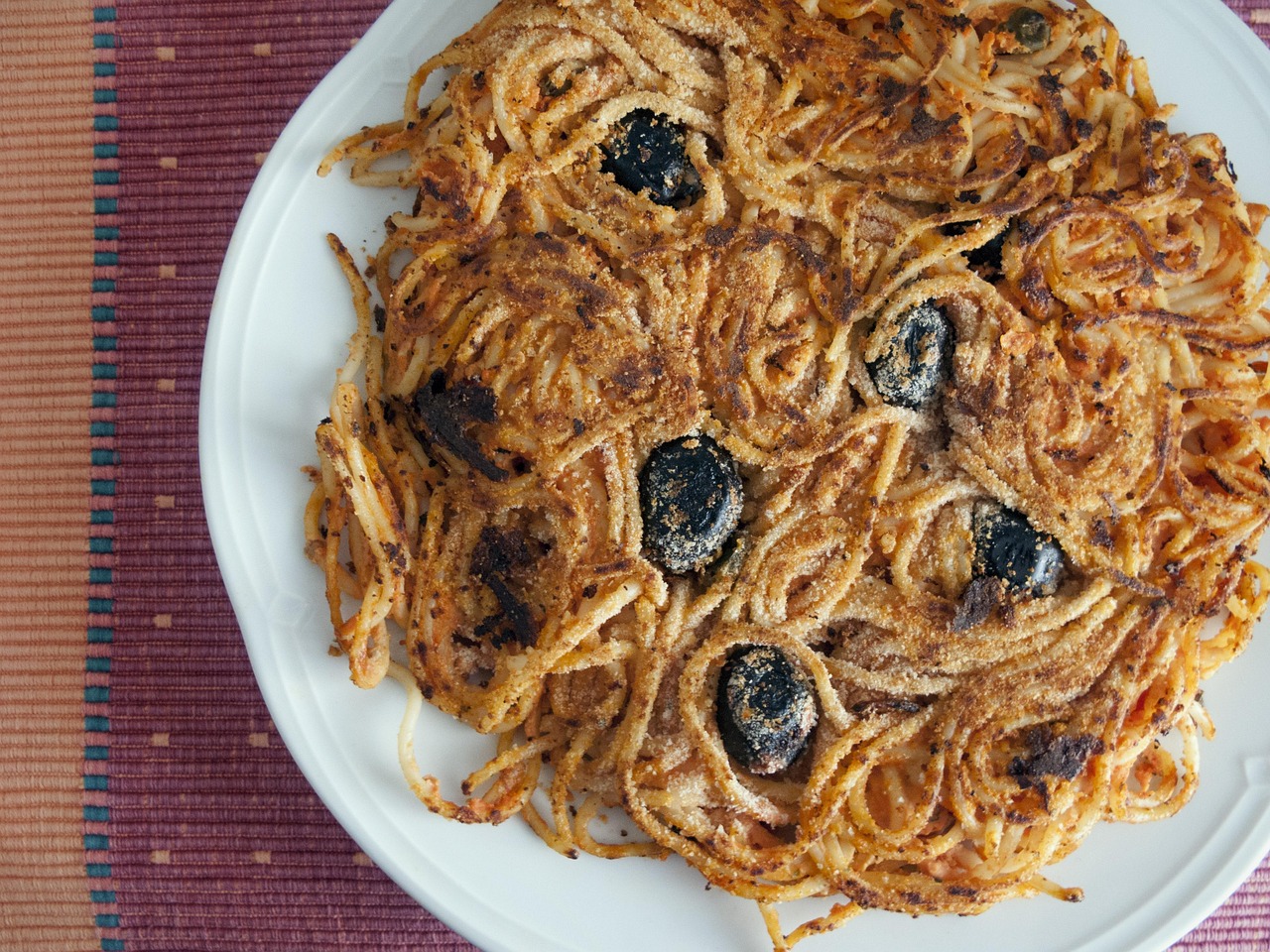 Pasta al forno croccante con pane grattugiato e fiocchetti di burro sopra.