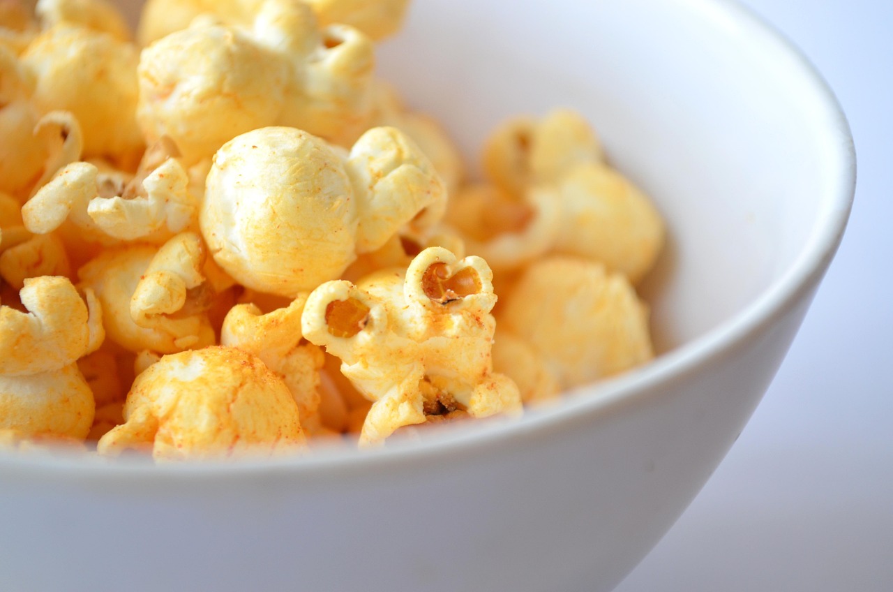 Popcorn aromatizzati con spezie e burro fuso in un recipiente colorato.
