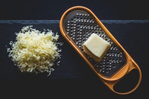 Formaggio grattugiato in un contenitore, pronto per essere congelato per conservarne freschezza e qualità.