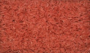Immagine di carne macinata in vaschetta con colorazione grigia sul fondo.