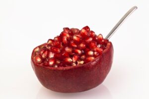 Melograno tagliato a metà con cucchiaio pronto per essere battuto per sgranare i semi.