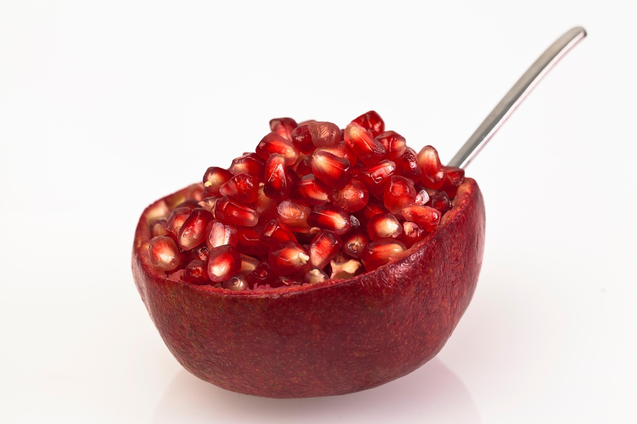 Melograno tagliato a metà con cucchiaio pronto per essere battuto per sgranare i semi.