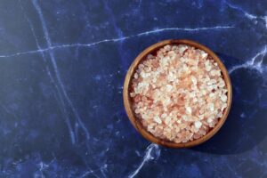 Confronto tra sale rosa dell'Himalaya e sale marino su sfondo neutro.